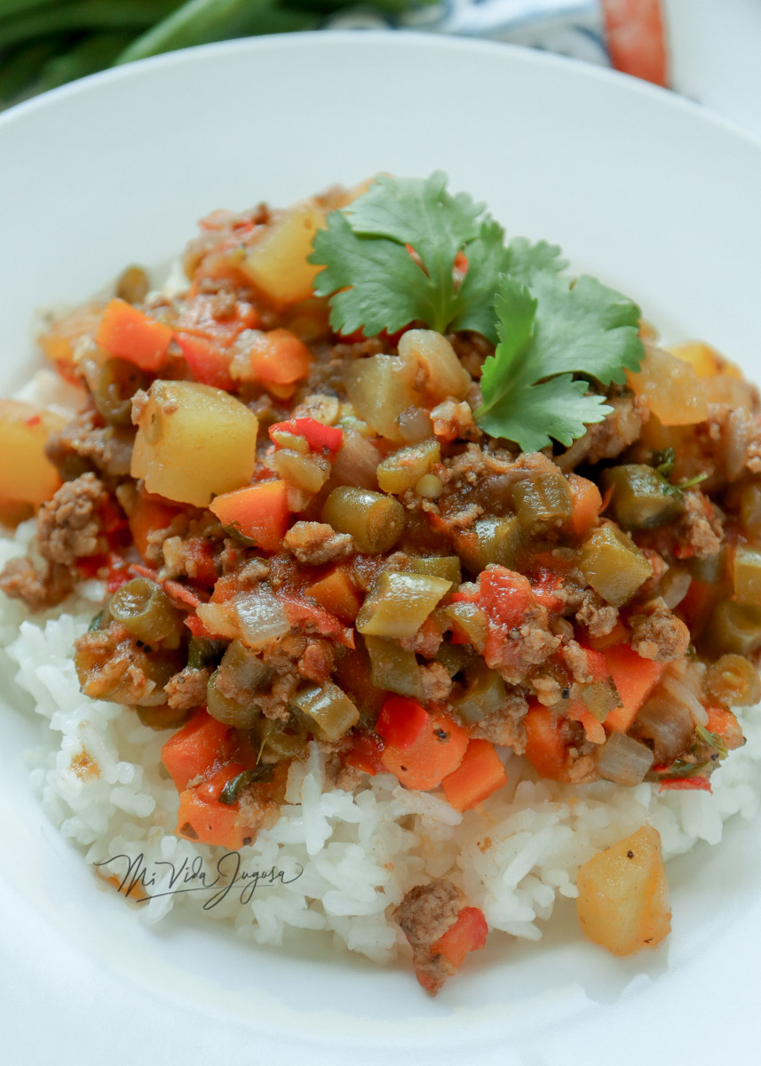 Picadillo final, servido sobre una cama de arroz blanco y decorado con una hojita de culantro.