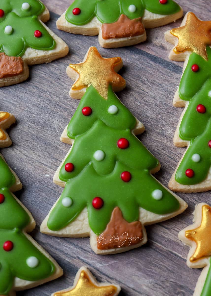 Galleta de mantequilla en forma de arbol navideño decorado con estrella amarilla y luces navideñas. Glaseado real sin claras está seco para mostrar producto final