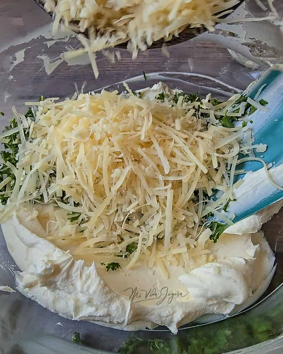 Se agrega el queso parmesano a la mezcla de queso crema con perejil