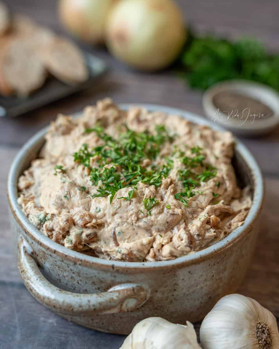 Un tazon redondo donde muestra el dip de cebolla caramelizado decorado con perejil por arriba