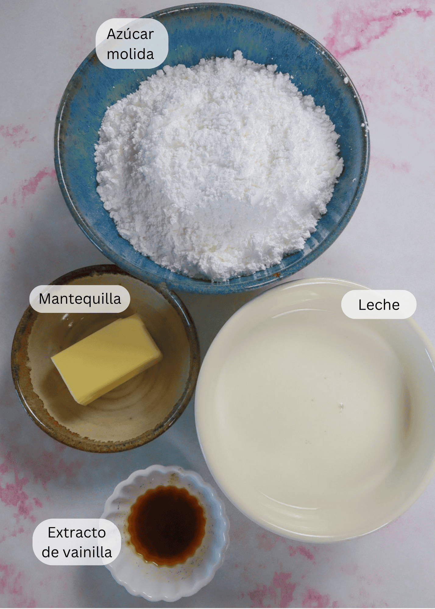 4 diferentes tacitas conteniendo los ingredientes: Azúcar glas, leche, mantequilla y vainilla.