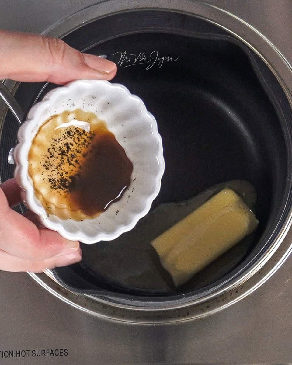 Olla pequeña conteniendo media barra de mantequilla y una tacita con vainilla , lista para ser agregada