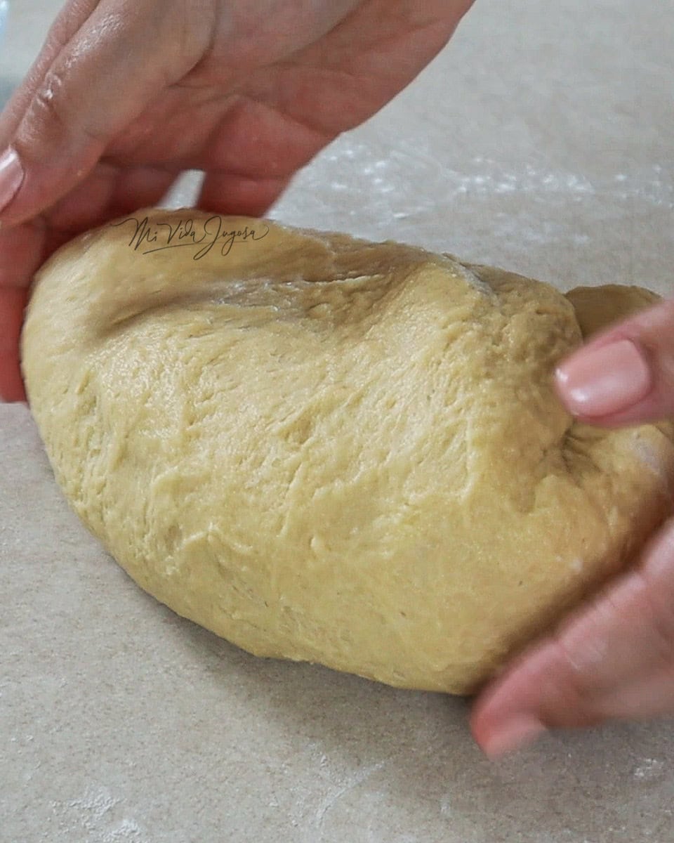 Dos manos colocando la masa en una mesa plana y enharinada