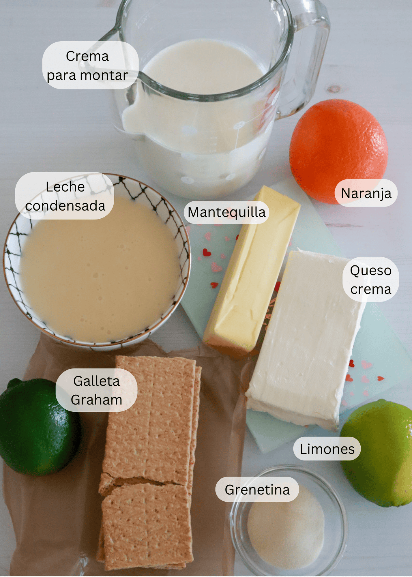 Ingredientes del pay de limón: Crema para montar, leche condensada, mantequilla, una naranja, galletas Graham, queso crema, grenetina y dos limones