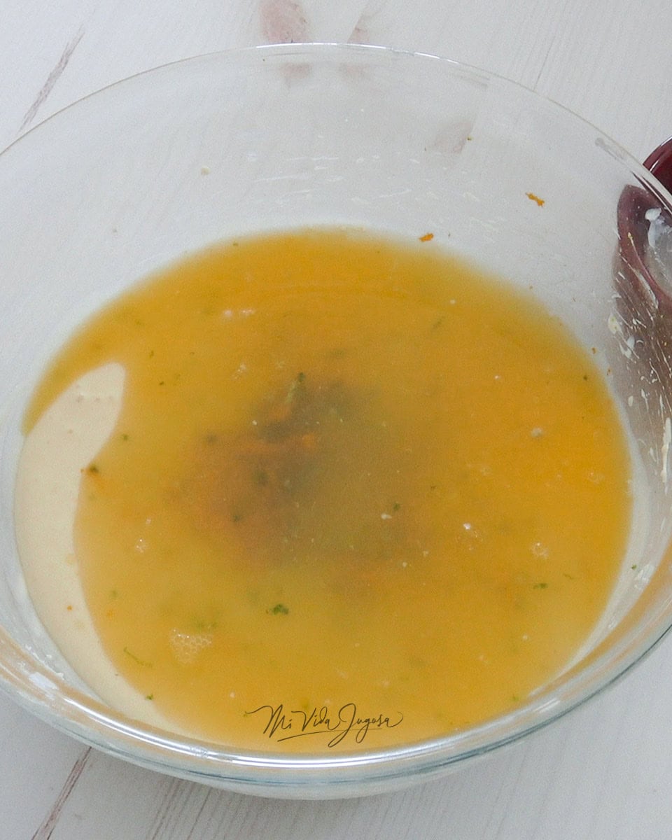 Se agregan los jugos de limón y de naranja a la mezcla del queso crema que se encuentra en un tazon transparente