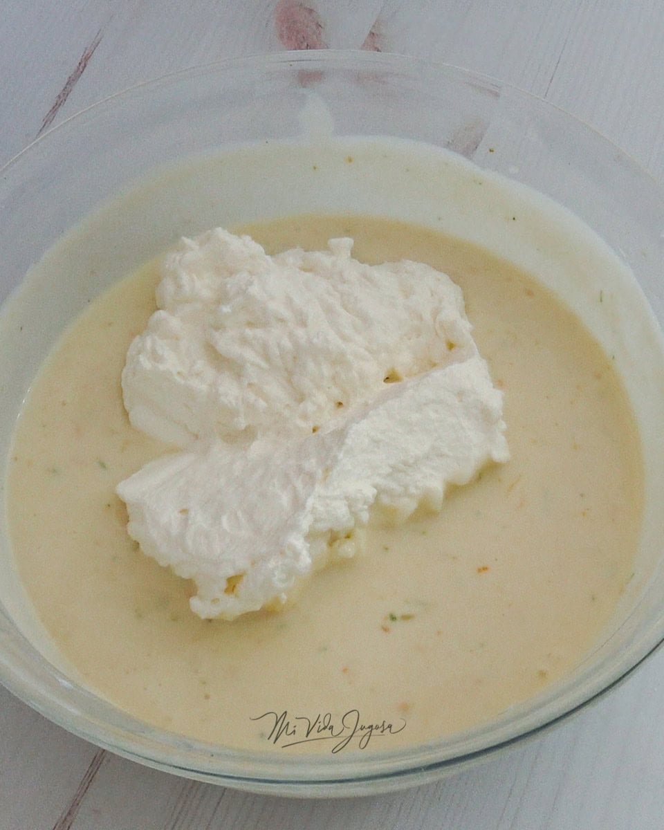 Se agrega crema montada o batida a la mezcla de queso crema, leche condensada, ralladuras y jugos de limón y naranja