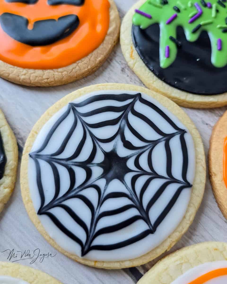 Galleta decorada en forma de telaraña, el fondo de color blanco y la telaraña de color negro