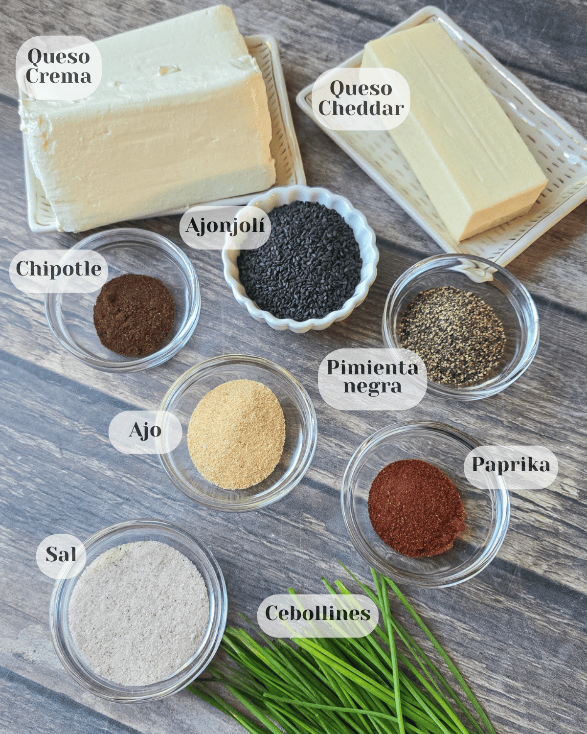 Se muestran diferentes tacitas las cuales incluyen: Queso crema, queso cheddar, chipotle molido, semillas de ajonjolí, pimienta negra, ajo, paprika, sal, cebollines.