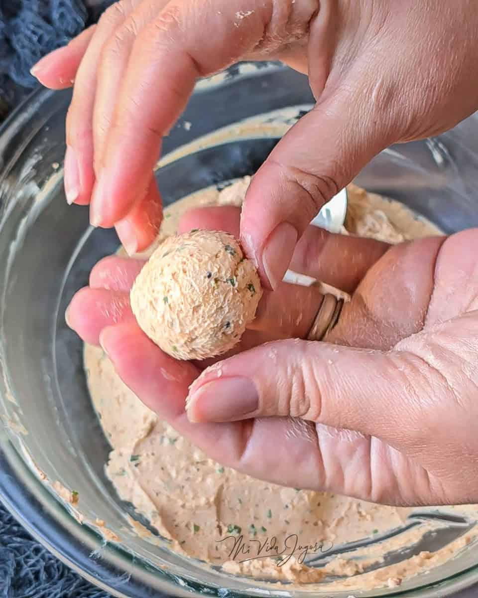 Las manos de Mara mostrando una bolita de la mezcla, con el tazón de fondo