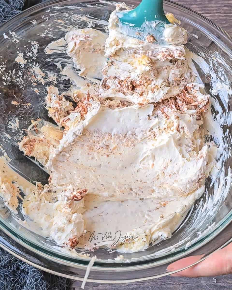 Se muestra el tazón de vidrio con una mezcla de los quesos y los ingredientes molidos