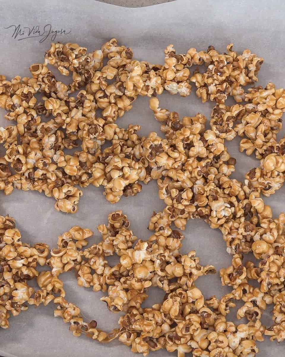 Una bandeja de aluminio cubierta de papel encerado conteniendo las palomitas bañadas en caramelo en forma extendidas