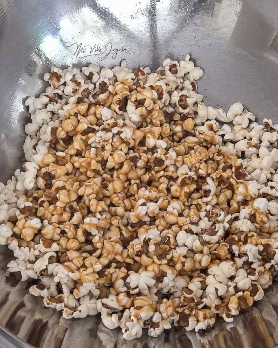 Un tazón de aluminio con las palomitas y el caramelo encima, listos para ser mezclados