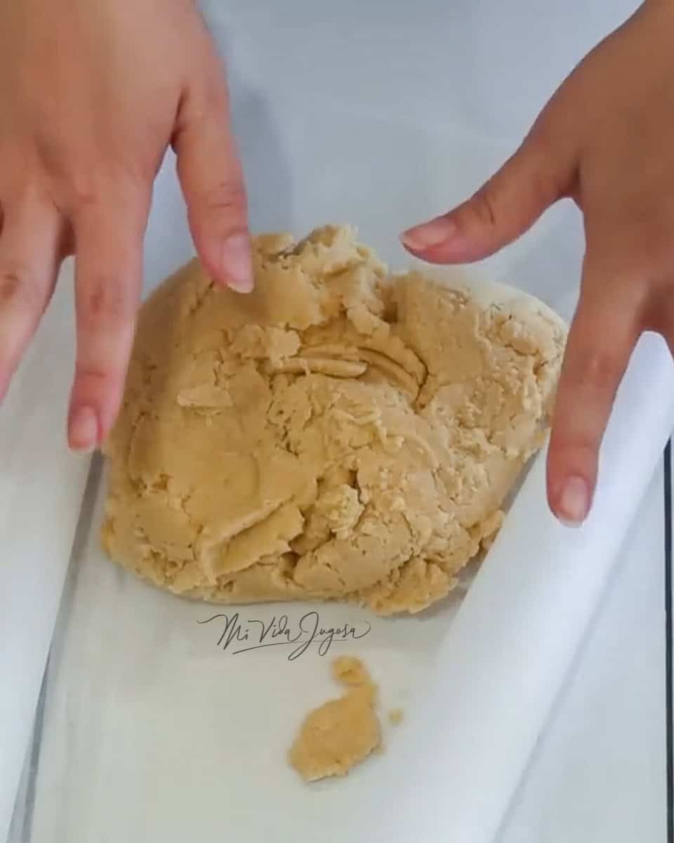 Una bola de masa sobre un papel pergamino, y dos manos por encima