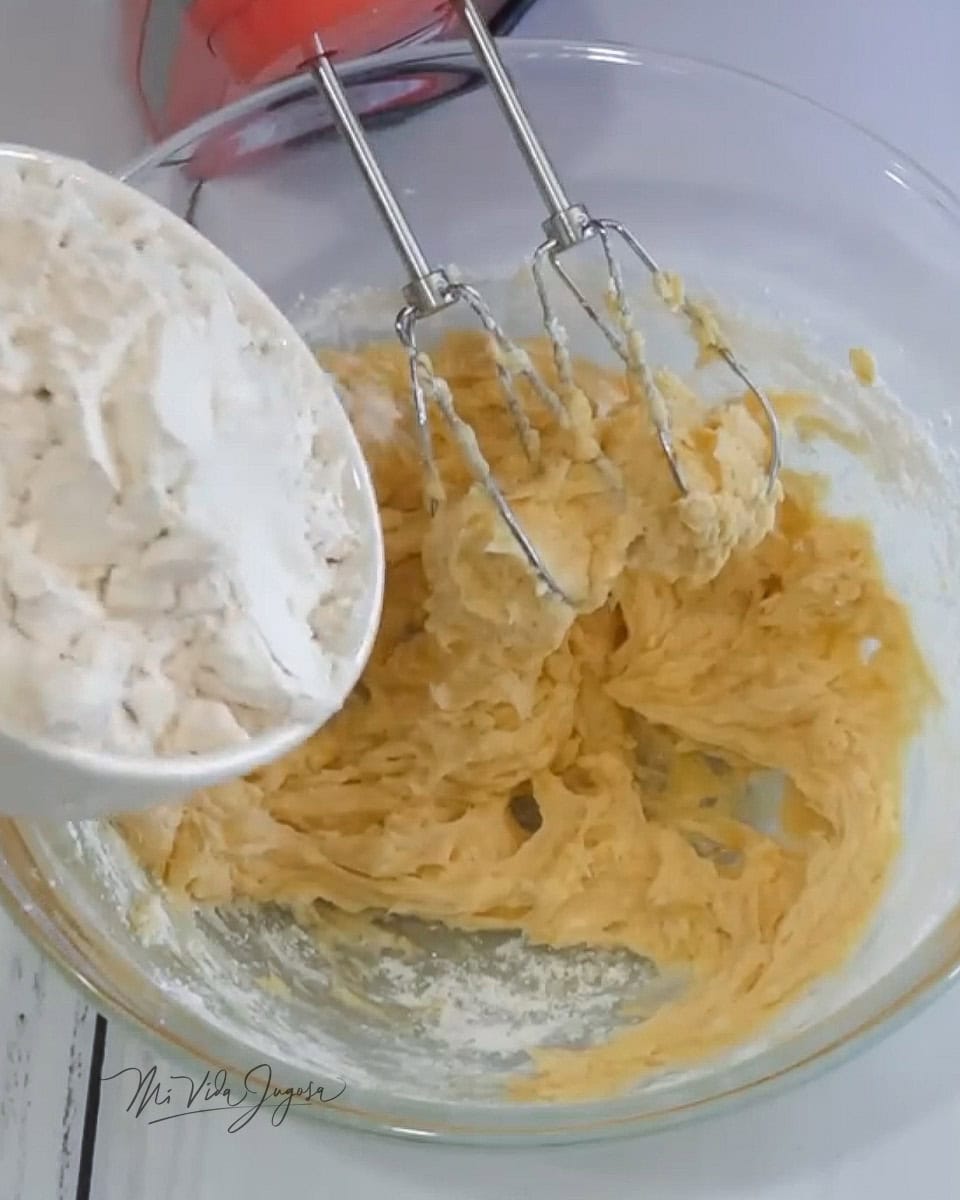 Un tazón con la base de los ingredientes a la cual se le esta agregando la harina 