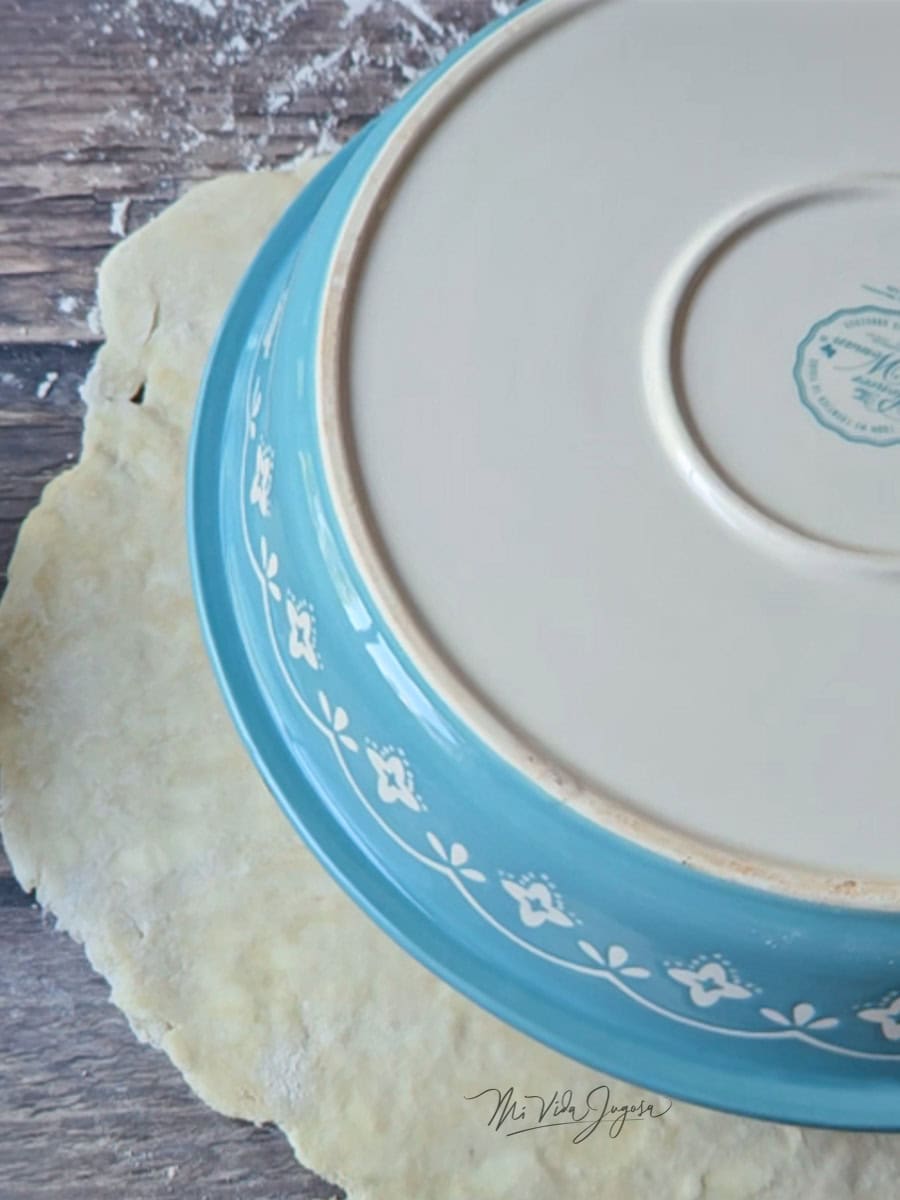 Una mesa con la masa extendida sobre ella, con un molde boca hacia abajo, para pie sobre la masa.