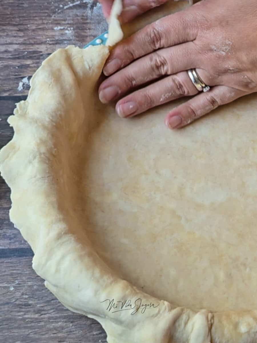 Una mano presionando suavemente la masa dentro del molde mientras ajusta los bordes.