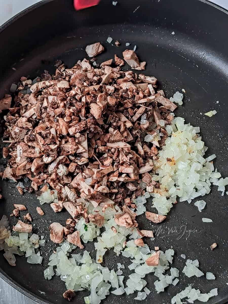 un sarten conteniendo cebolla y hongos picados