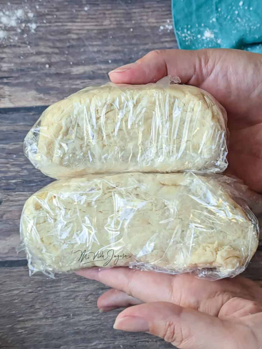 Dos bolas de masa compacta envueltas en papel plástico, sostenidas por ambas manos.