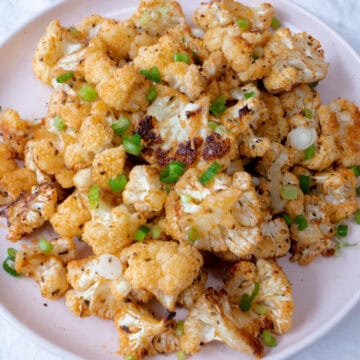 Un plato con floretes de coliflor cocinados y decorados por encima con pedacitos de cebollino