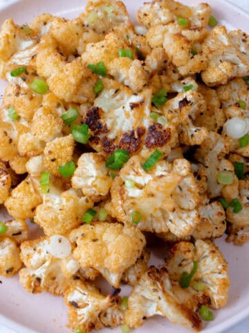 Un plato con floretes de coliflor cocinados y decorados por encima con pedacitos de cebollino