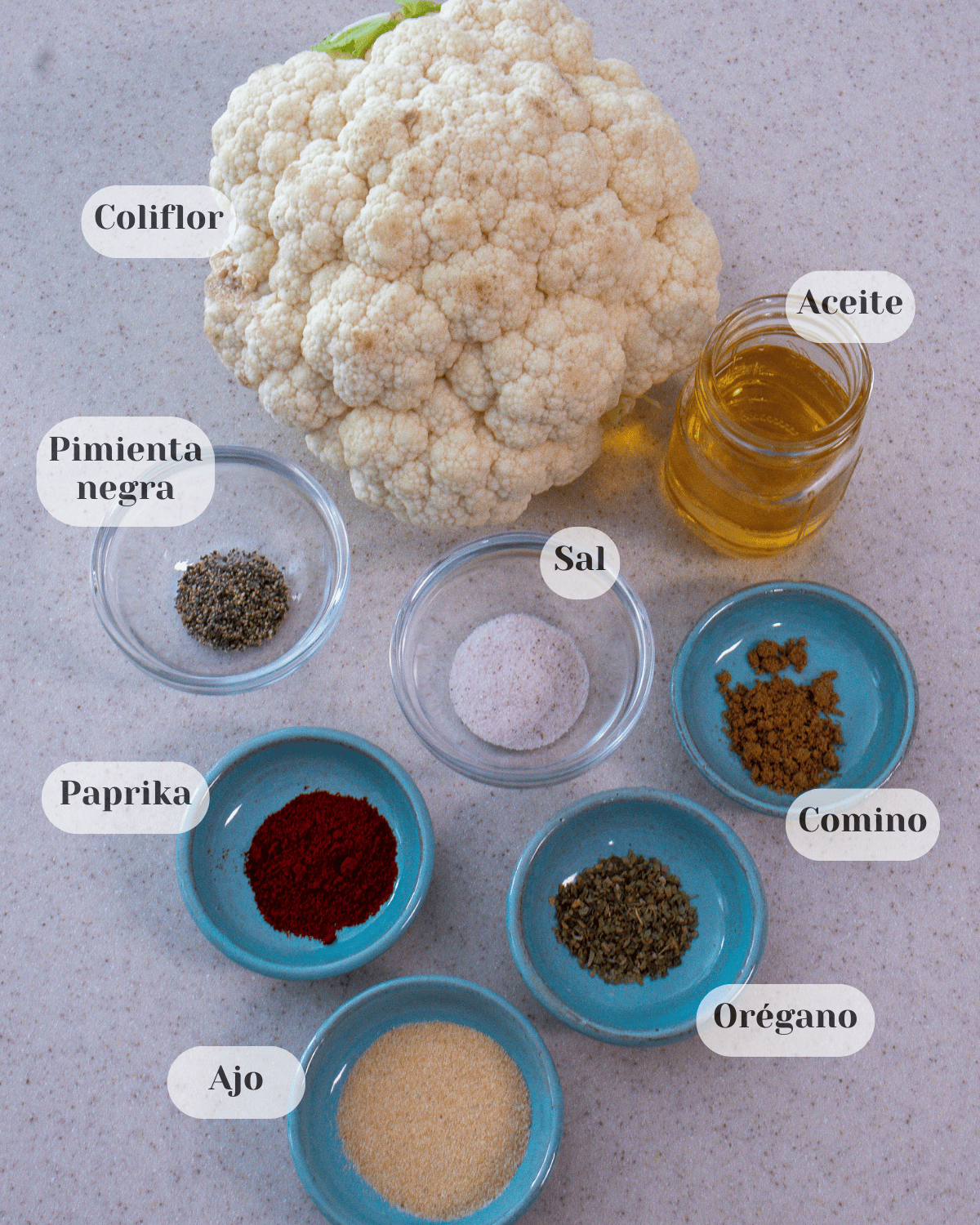 Una coliflor entera, un vaso pequeno conteniendo aceite, seis tazas conteniendo pimienta negra, sal, comino, orégano, paprika y ajo
