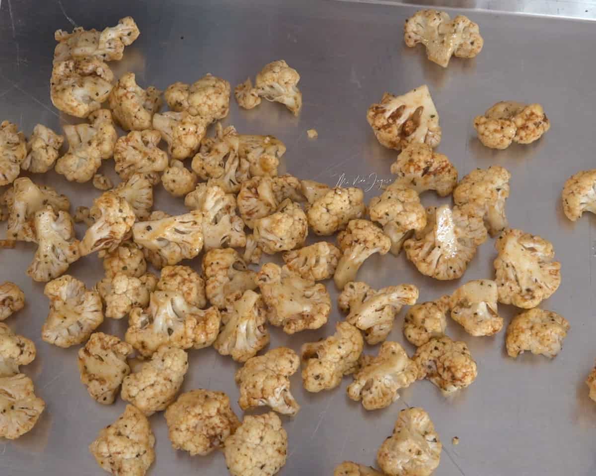 Los floretes de coliflor condimentados esparcidos sobre una bandeja de aluminio.