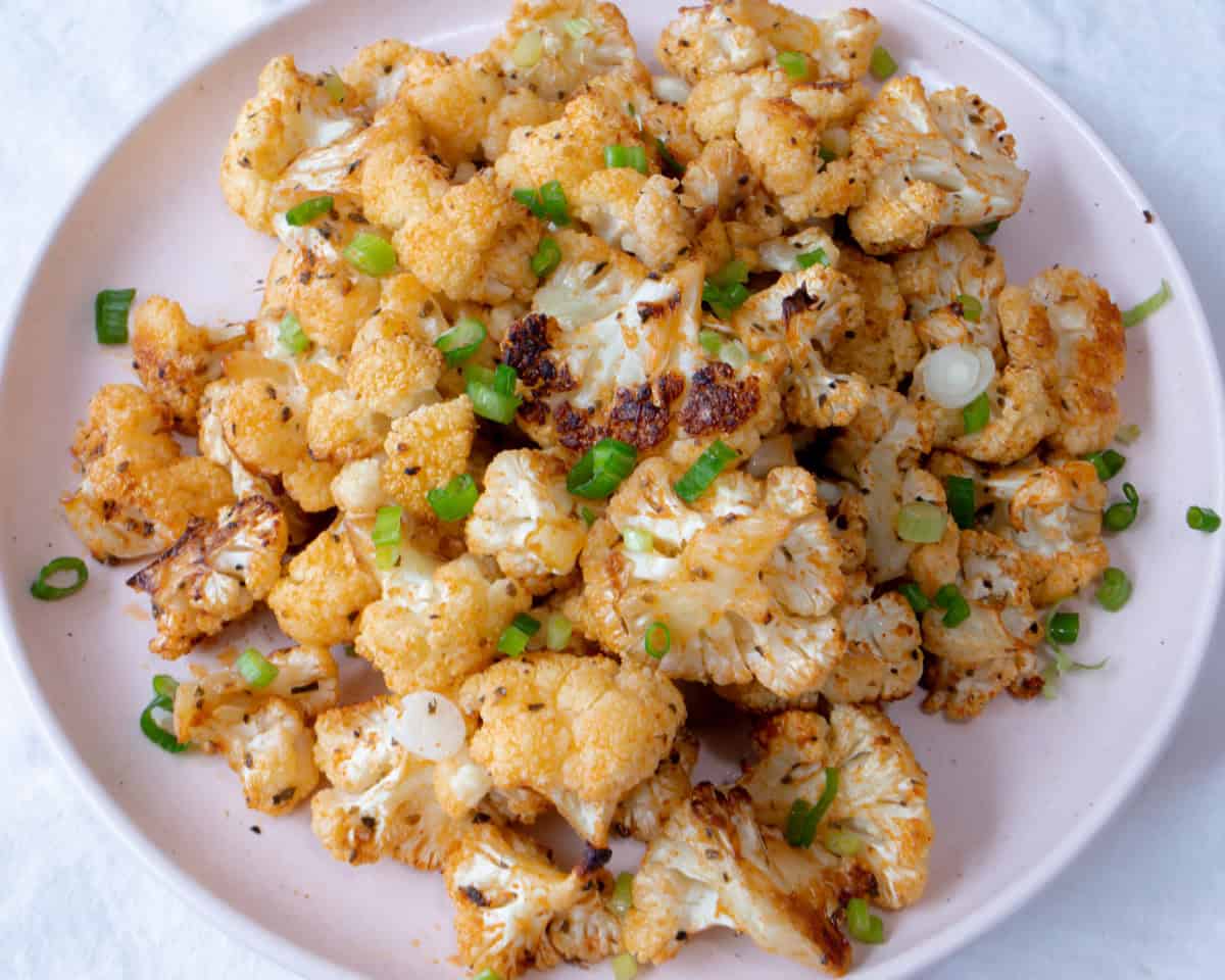 Un plato con rosetas de coliflor cocinadas, y decoradas por encima con cebollinos 