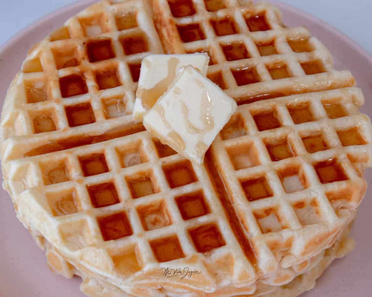 Un waffle servido con unos trocitos de mantequilla encima y sirope de maple