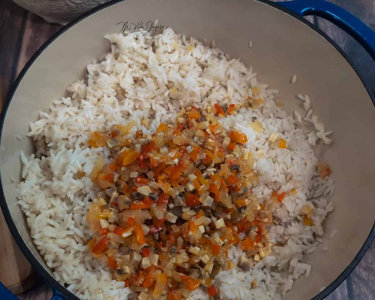 Una olla con arroz blanco y una mezcla de chile dulce y cebolla por encima.