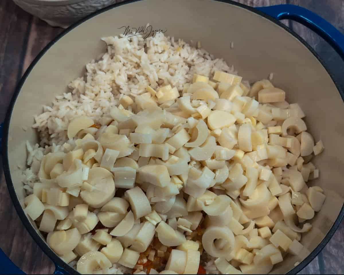 Una olla de arroz blanco con trozos de palmito por encima.