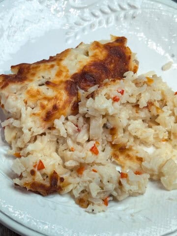 Un plato blanco con arroz cremoso y pedacitos de palmito, cubierto con queso gratinado por encima.