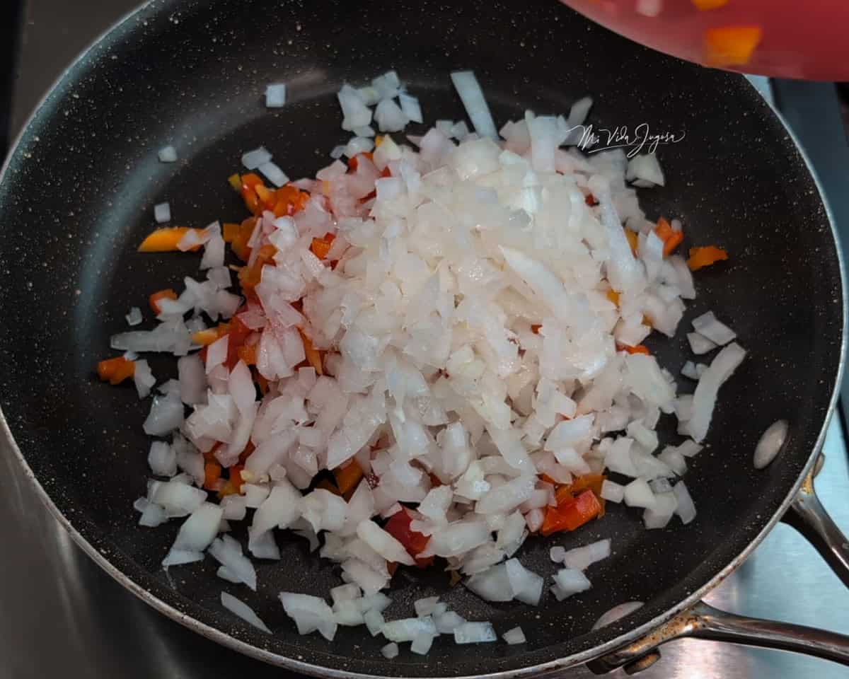Un sartén con pedacitos de cebolla y chile dulce.