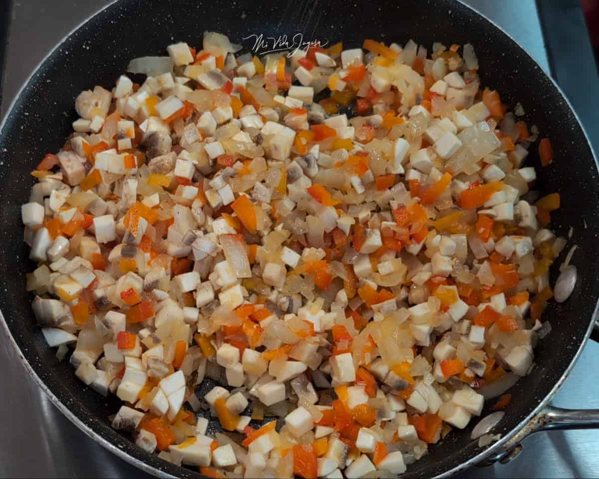 Un sartén con chile dulce, cebolla y pedacitos de hongos.