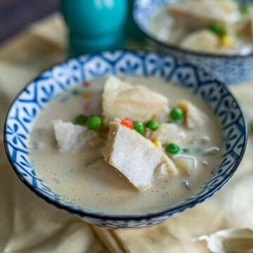 Un tazón azul con sopa de bacalao, donde se observan pedazos de bacalo con arvejas y caldo de la sopa.