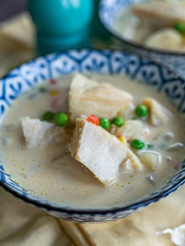 Un tazón azul con sopa de bacalao, donde se observan pedazos de bacalo con arvejas y caldo de la sopa.