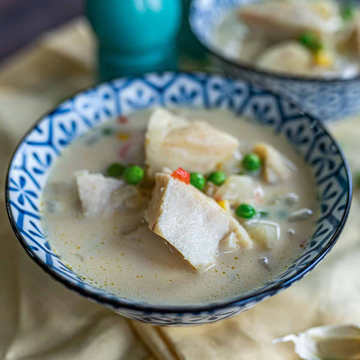 Un tazón azul con sopa de bacalao, donde se observan pedazos de bacalo con arvejas y caldo de la sopa.