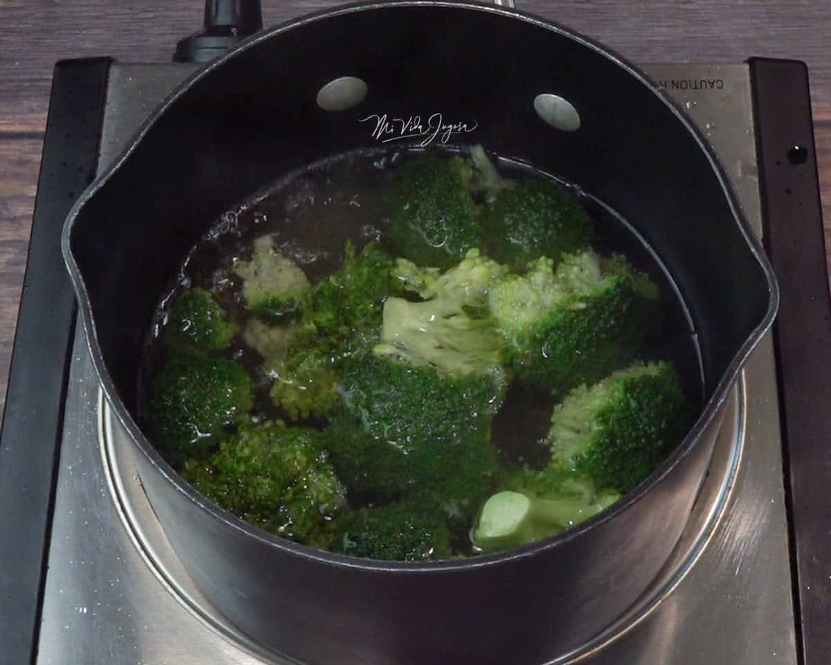 En una cocina se encuentra una olla pequeña con trozos de brócoli.