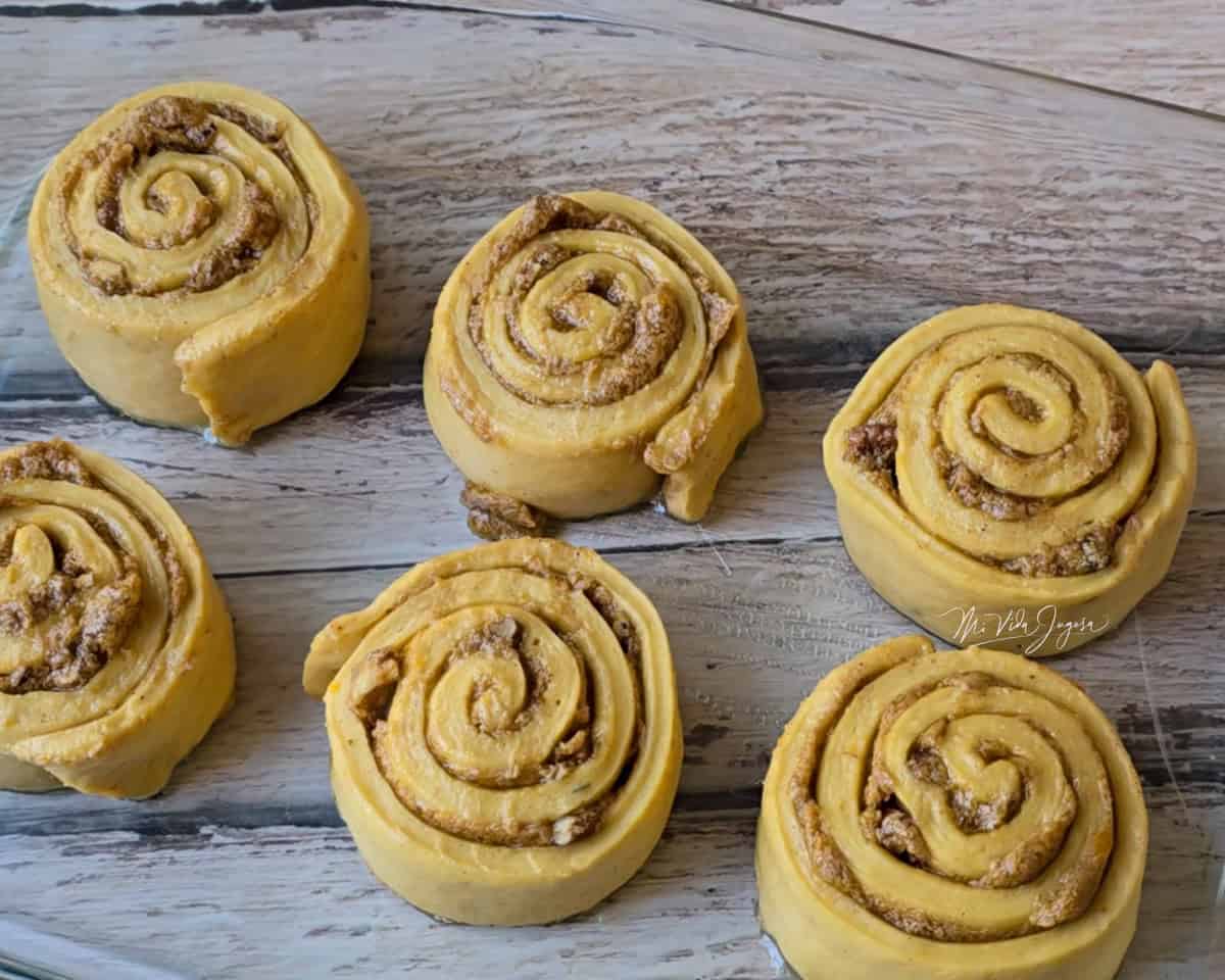Seis rollos de calabaza con pecanas colocados sobre un superficie plana.