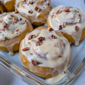 4 rollos de calabaza cubiertos de glaseado de queso crema y maple, decorados con pecanas finamente picadas