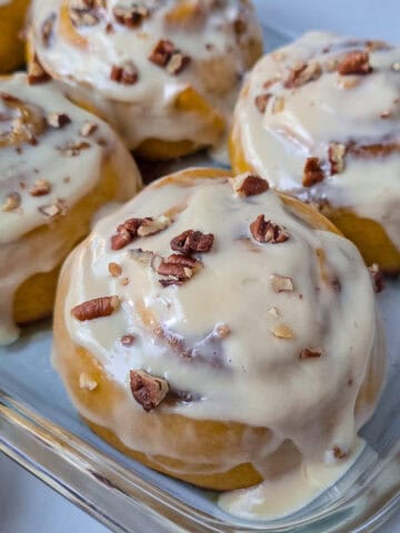 4 rollos de calabaza cubiertos de glaseado de queso crema y maple, decorados con pecanas finamente picadas