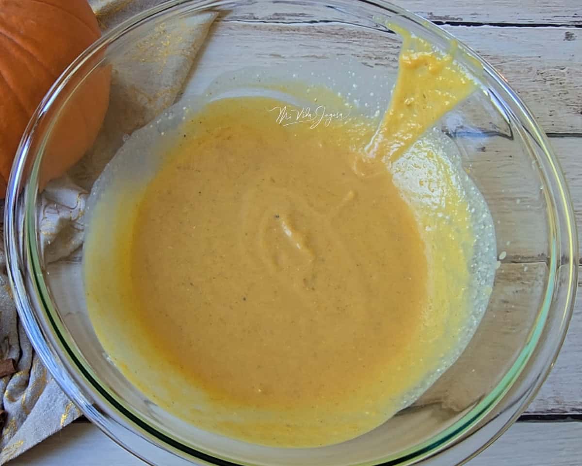 Un tazón de vidrio con la mezcla de puré de calabaza, azúcar morena, y levadura.
