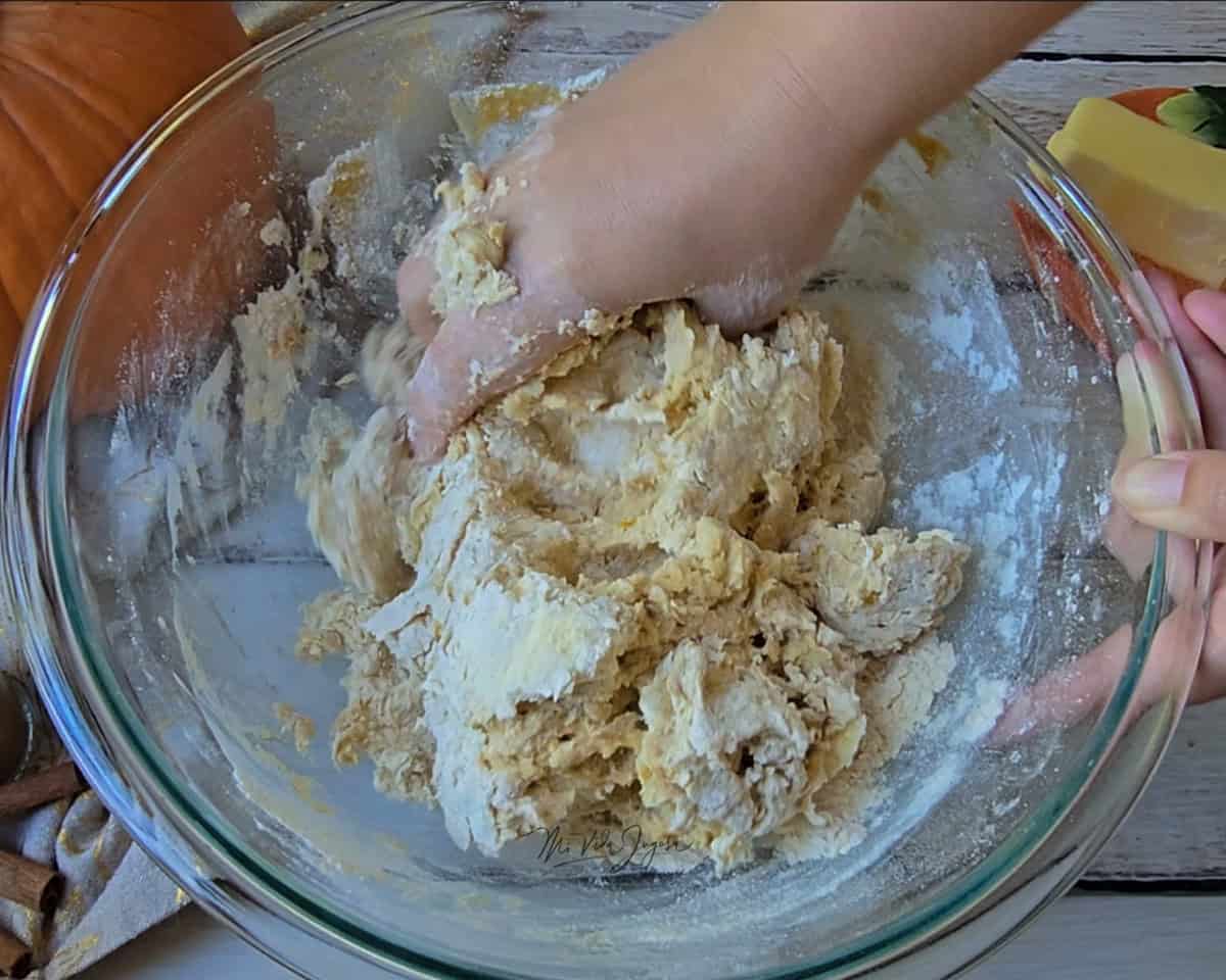Un tazón que contiene la mezcla de la masa, siendo revuelta con una mano.