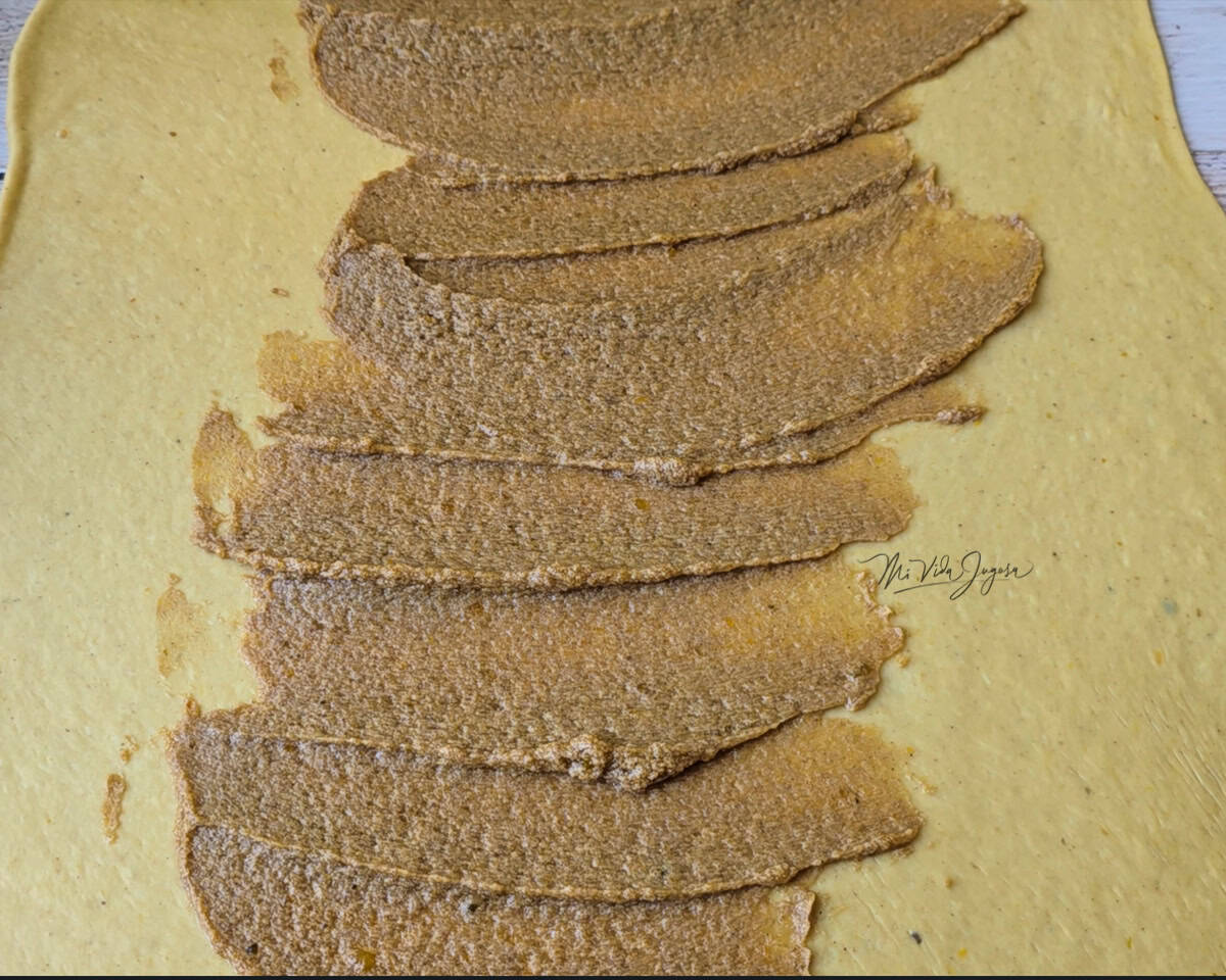 La masa estirada con una mezcla de azúcar y mantequilla por encima.