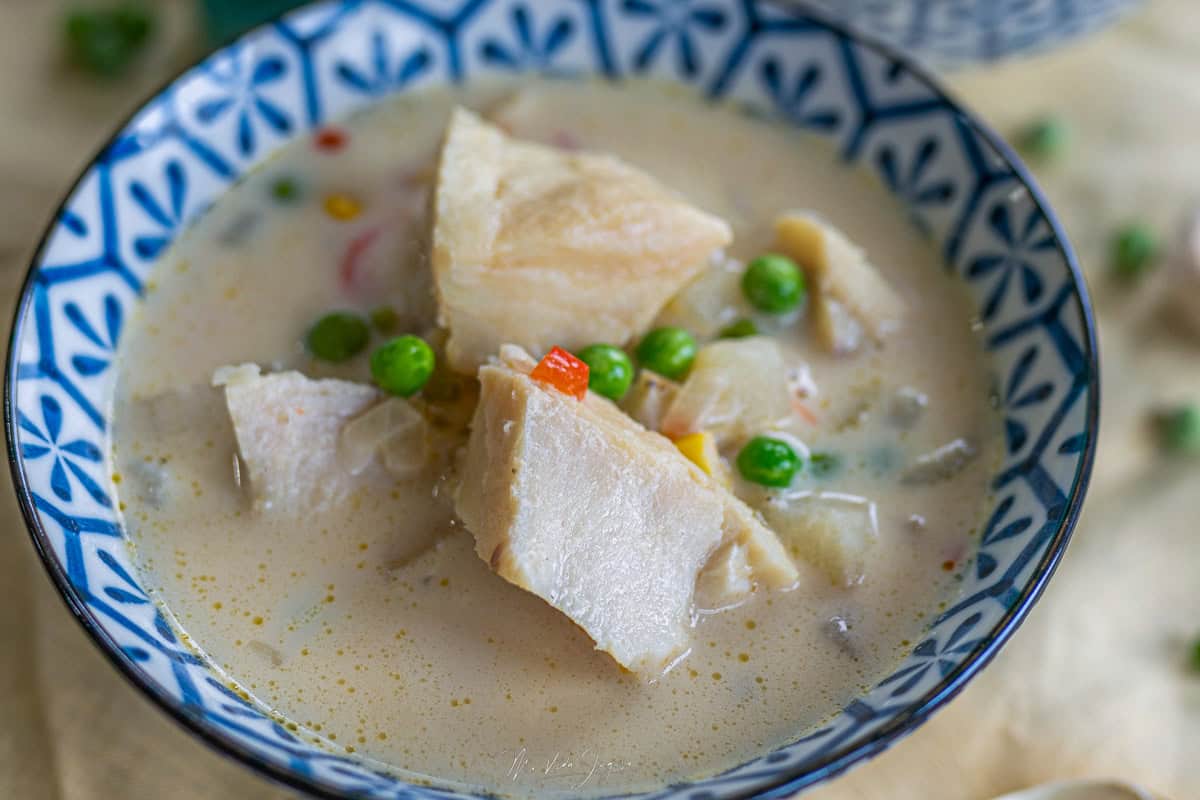 Un tazón azul con la sopa de bacalao, donde se observas pedazos de bacalao con arvejas y caldo.