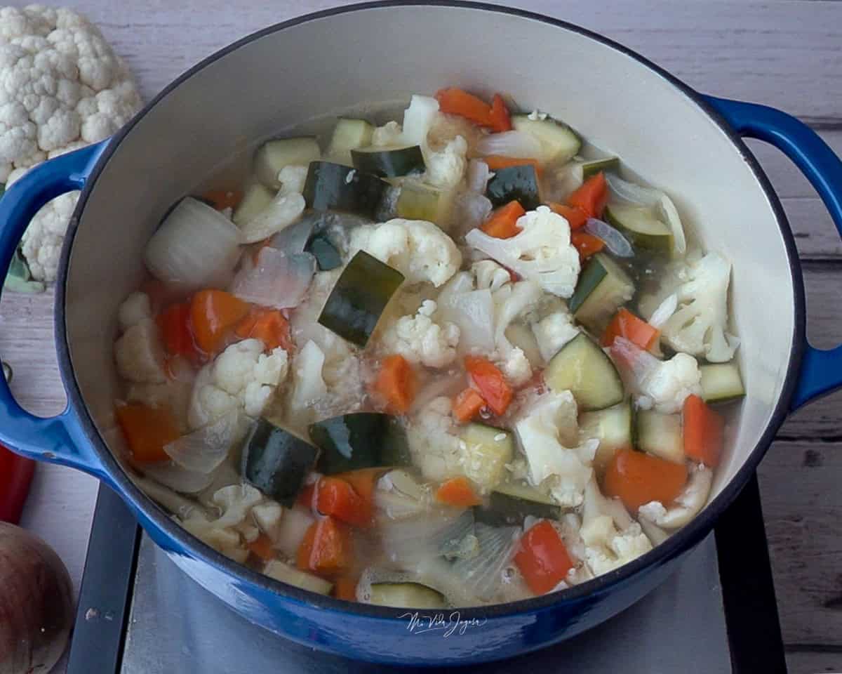 Una olla con vegetales picados en cuadritos y agua.